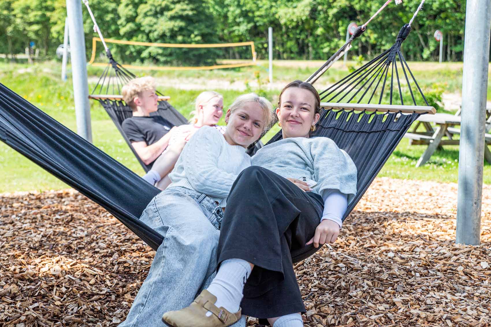Elever slapper af sammen i hængekøjer på udearealerne ved Husby Efterskole