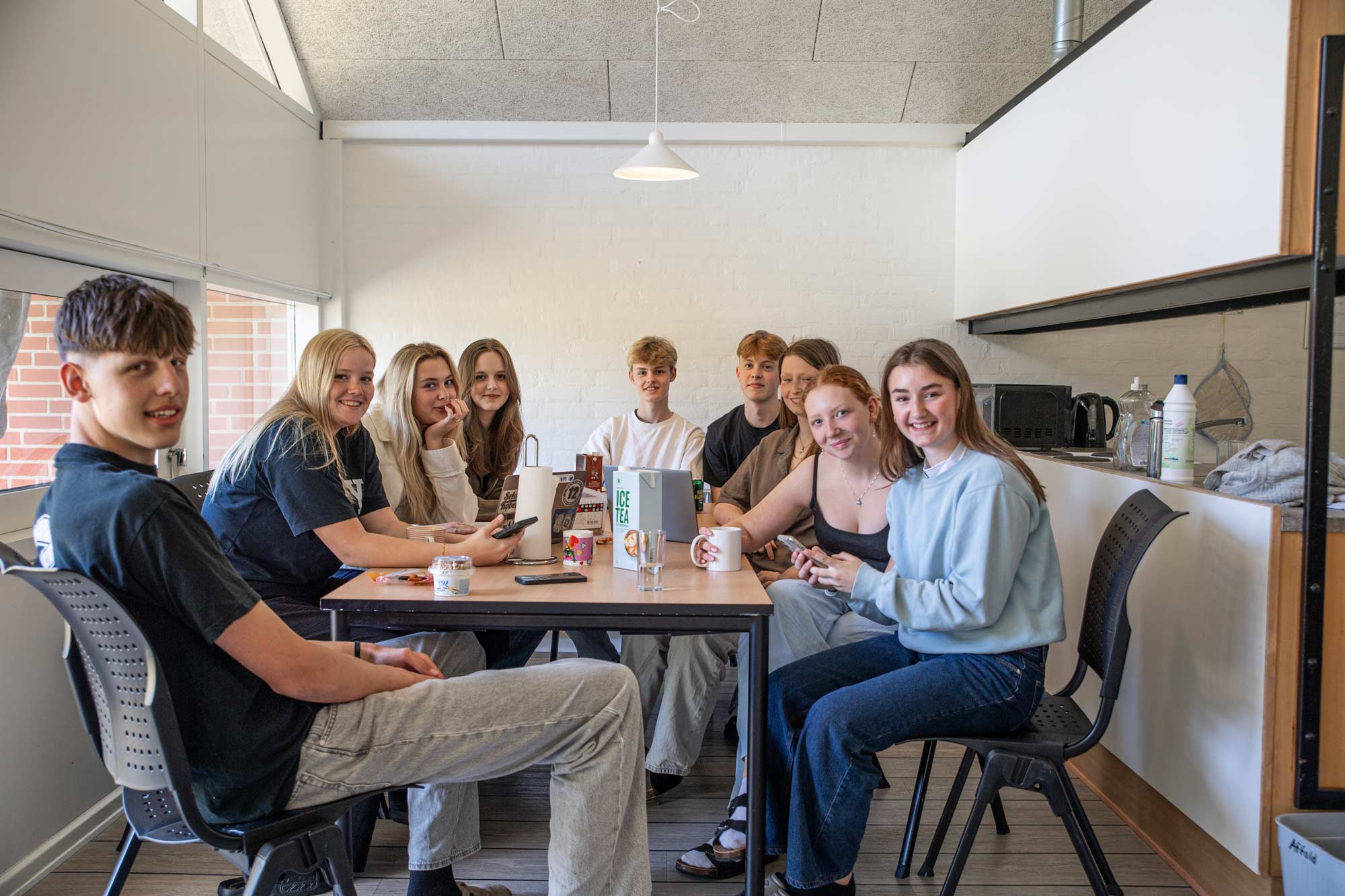 Elever samlet omkring bordet i et fællesområde på Husby Efterskole.