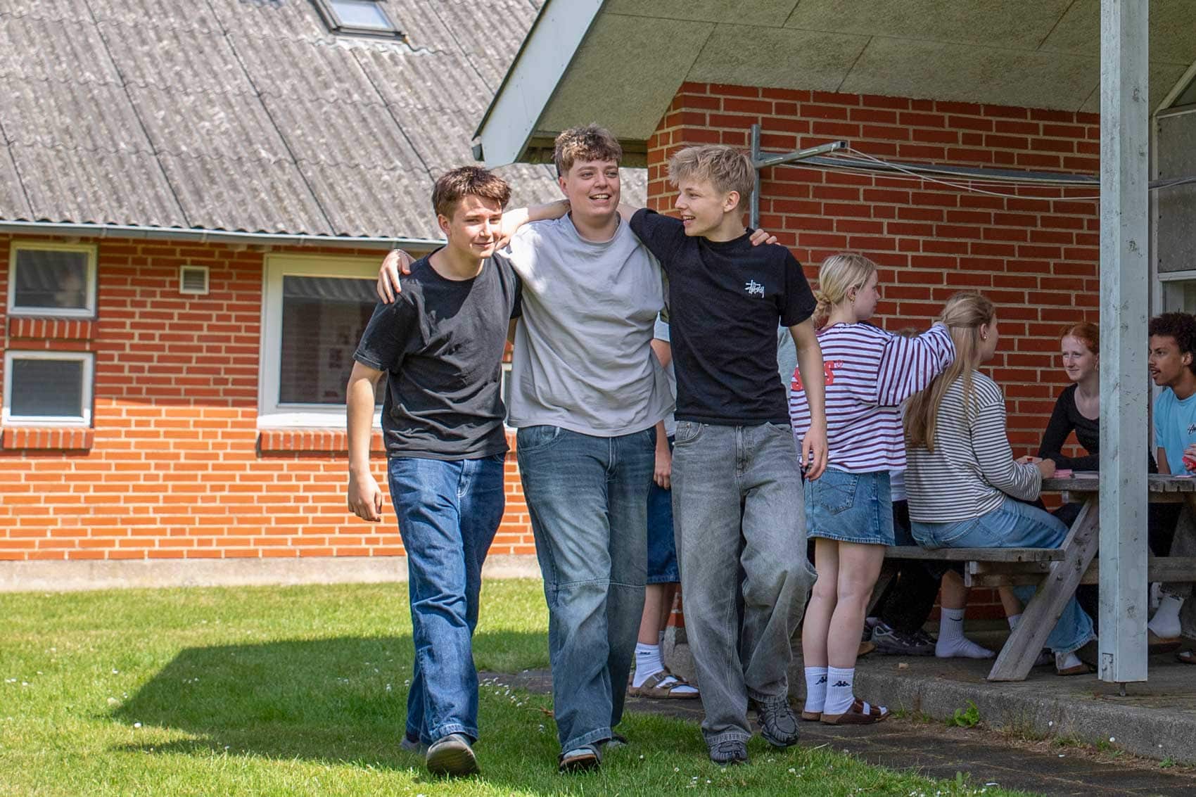 Tre elever går sammen på skolens udearealer på Husby Efterskole